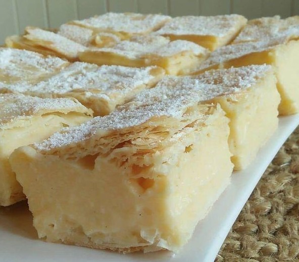 Indulge in Vanilla Custard Cream Squares: A heavenly dessert featuring layers of crispy puff pastry and luscious vanilla custard, topped with whipped cream. A delightful treat for your taste buds.