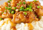 A delicious plate of Instant Pot Honey Garlic Chicken garnished with green onions, served over a bed of fluffy rice, with a drizzle of honey garlic sauce.