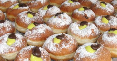 A plate of delicious and fluffy mini brioche donuts filled with sweet pastry cream.