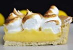A slice of Grandma's Magic Lemon Pie on a plate, with a dollop of whipped cream on top.