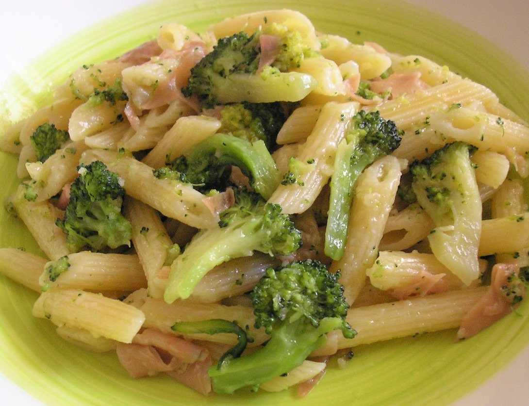 A plate of penne pasta with broccoli, tuna, and broccoli cheddar sauce, topped with Parmesan cheese.