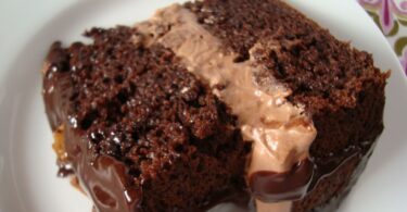 A slice of Ding Dong Coffee Cake on a white plate. Satisfy your sweet tooth with this decadent Ding Dong Coffee Cake. This chocolate cake is filled with a creamy peanut butter filling, making it a delicious treat any time of the day. Perfect for breakfast, dessert, or as an afternoon snack.