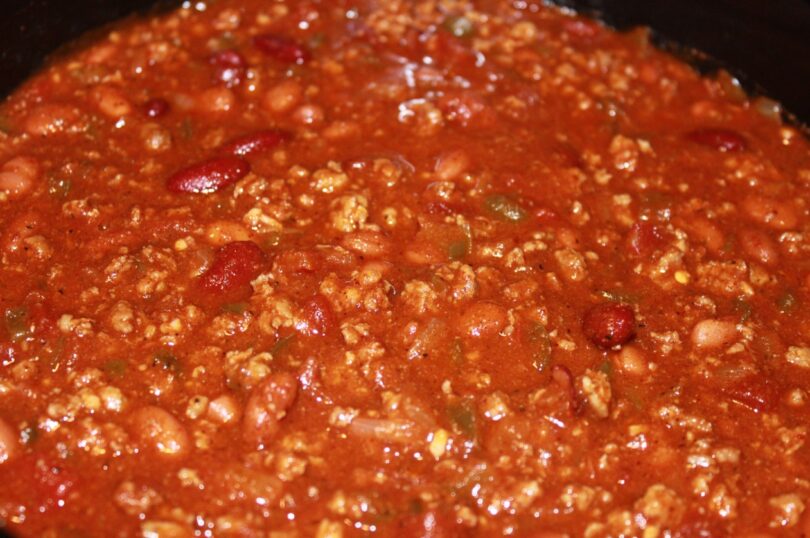 A bowl of homemade chili with ground beef, beans, and spices, topped with shredded cheese and sour cream. Satisfy your cravings for comfort food with this easy and delicious homemade chili recipe. Made with ground beef, beans, diced tomatoes, and a blend of spices, this chili is the perfect meal for any day of the week. Top with shredded cheese and sour cream for an added touch of flavor. Enjoy this warm and hearty chili in a bowl today!