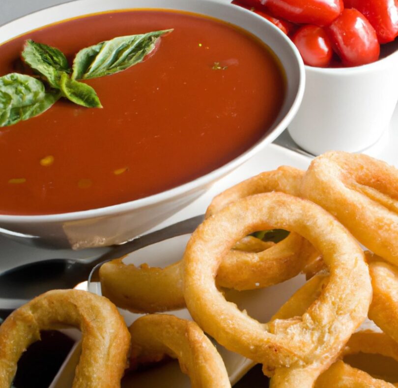 A steaming bowl of tomato basil soup paired with crispy, golden brown double-dipped onion rings.