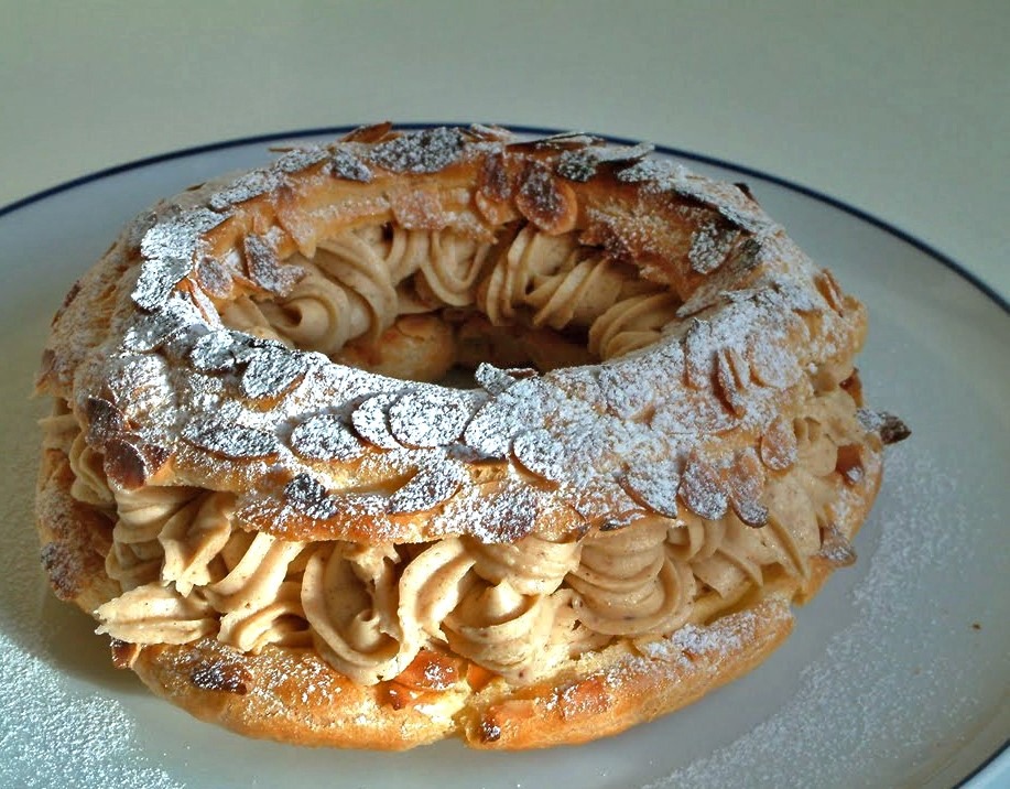 A round pastry filled with praline cream and sliced almonds on top, with powdered sugar sprinkled over it.