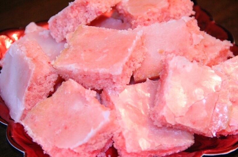 A slice of fresh and juicy strawberry brownies on a white plate.