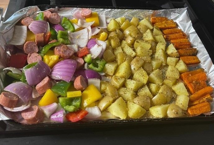 Image of a sheet pan filled with roasted beef sausage, sweet potatoes, onions, and bell peppers, seasoned with garlic powder, paprika, dried thyme, salt, and black pepper. This sheet pan sausage and vegetable recipe is a quick and easy meal that is perfect for busy weeknights or meal prep. The beef sausage is roasted alongside sweet potatoes, onions, and bell peppers, and seasoned with garlic powder, paprika, dried thyme, salt, and black pepper.
