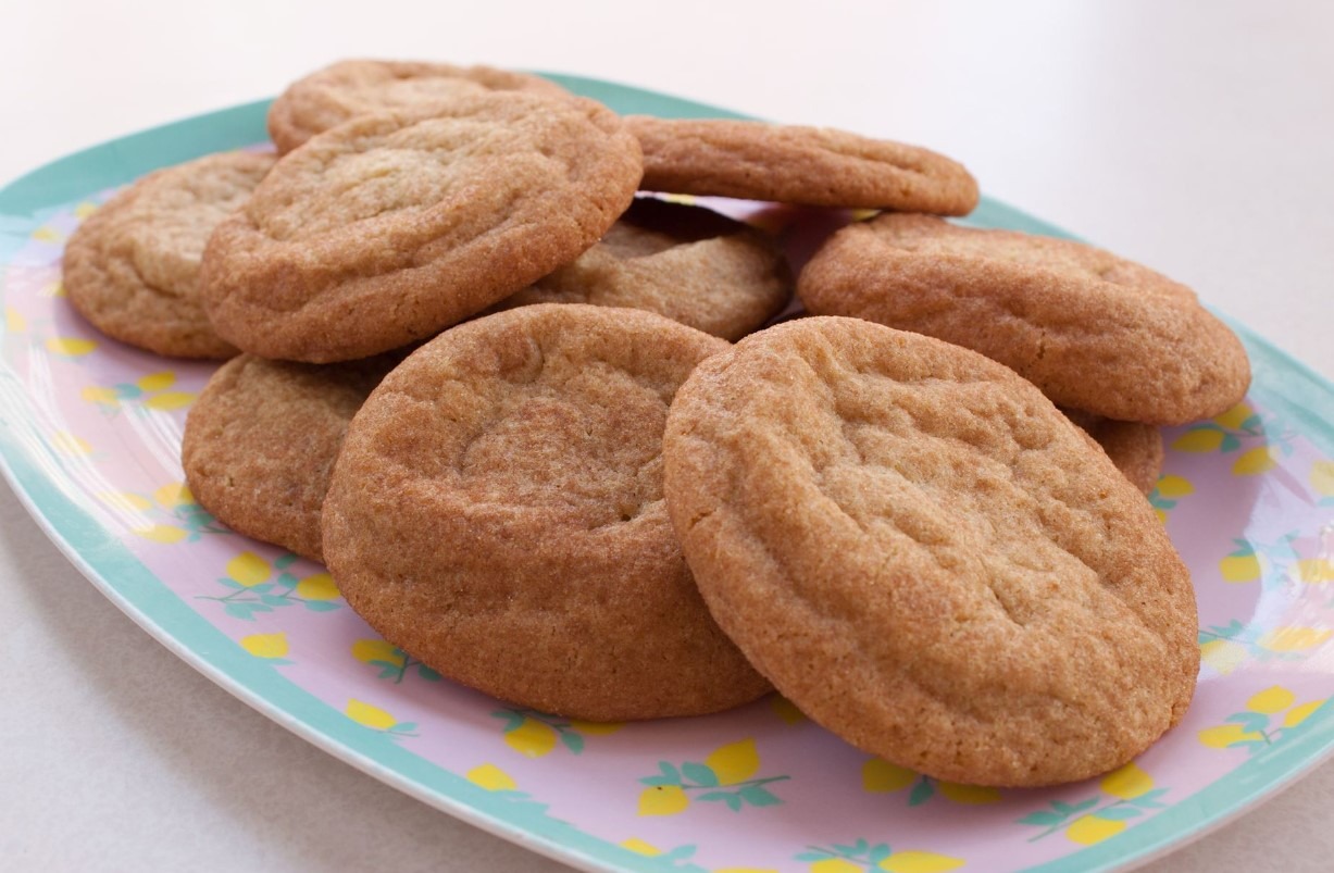A close-up photo of freshly baked snickerdoodle cookies, coated in a crackled cinnamon sugar mixture.