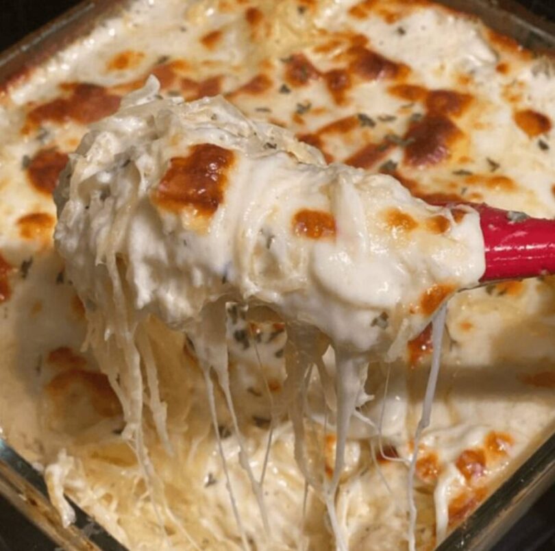 A delicious plate of chicken spaghetti topped with melted cheese and served with garlic bread and salad.